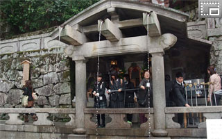 修学旅行で訪れた京都・清水寺で、音羽の滝の水を飲もうとしている生徒の写真です。